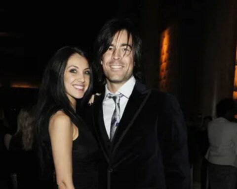 Smiling couple in formal wear posing together at a dimly lit gala or reception venue.