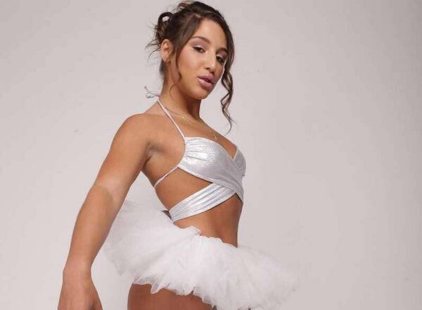 Woman in a silver wrap top and white tutu posing in a studio.