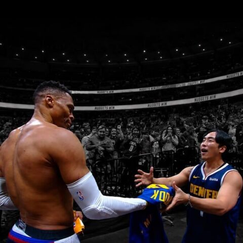 Post-game moment: a shirtless player with white arm sleeves shakes hands with a teammate in a Denver Nuggets jersey as the crowd cheers.