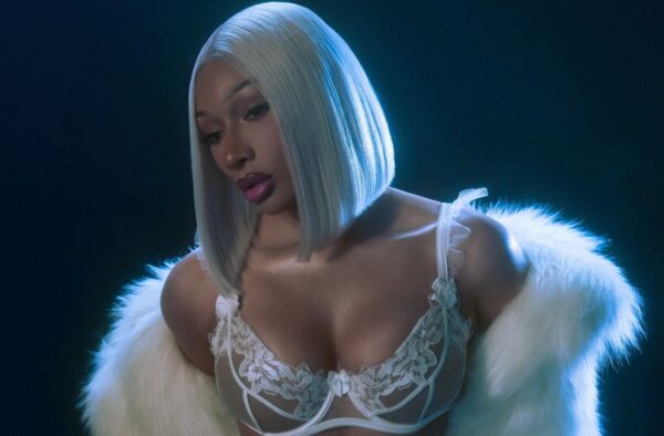 Portrait of a person with a platinum blue bob hairstyle, wearing white lace lingerie and a white fur stole, lit with cool blue lighting, looking downward in a contemplative pose.