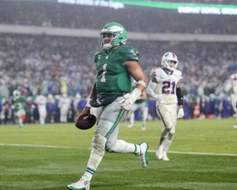 Philadelphia Eagles player in green #1 running with the ball downfield as a defender pursues nearby.