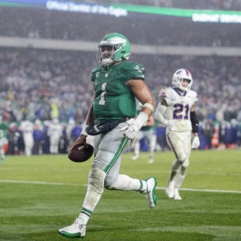 Philadelphia Eagles player in green #1 running with the ball downfield as a defender pursues nearby.