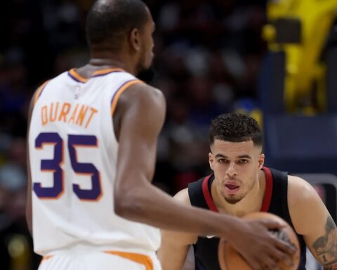Basketball action: player in a white Durant 35 jersey guards the ball against a defender in a dark jersey on the court.