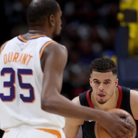 Basketball action: player in a white Durant 35 jersey guards the ball against a defender in a dark jersey on the court.