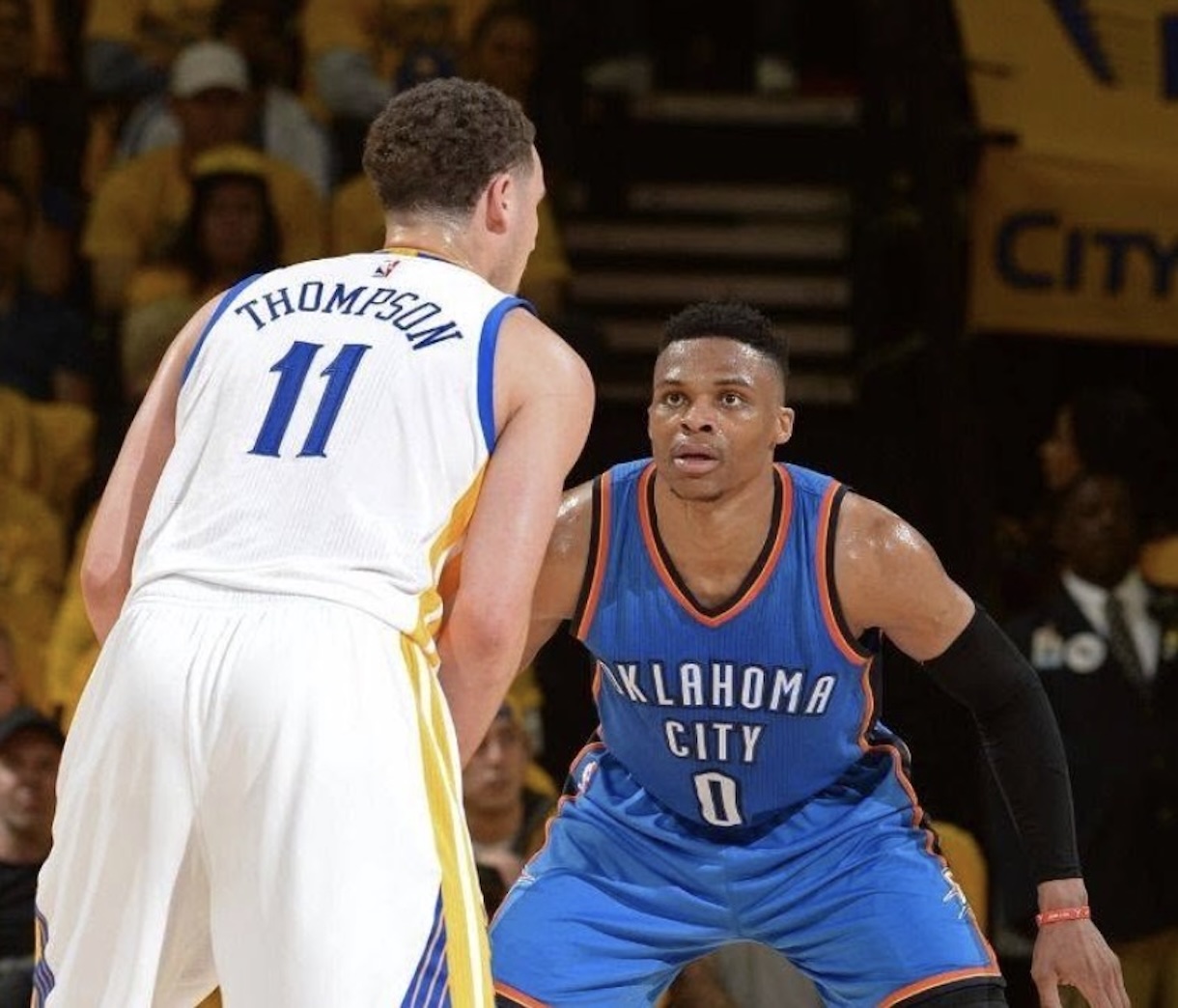 Basketball game action: Thompson wearing #11 in white defends against an Oklahoma City City player in blue.